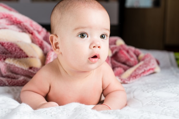 Beautiful happy small baby girl lying in bed