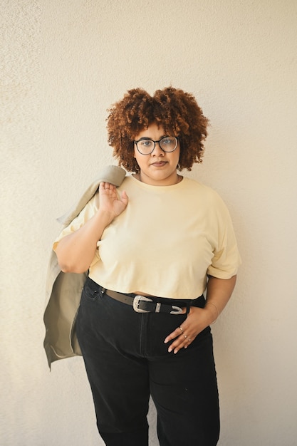 Foto bella felice sorridente curvy plus size donna nera africana capelli afro in posa jeans tshirt beige