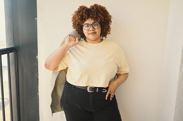 Photo beautiful happy smiling curvy plus size african black woman afro hair posing in beige tshirt jeans