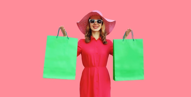 Beautiful happy smiling young woman model posing with shopping bags in summer hat