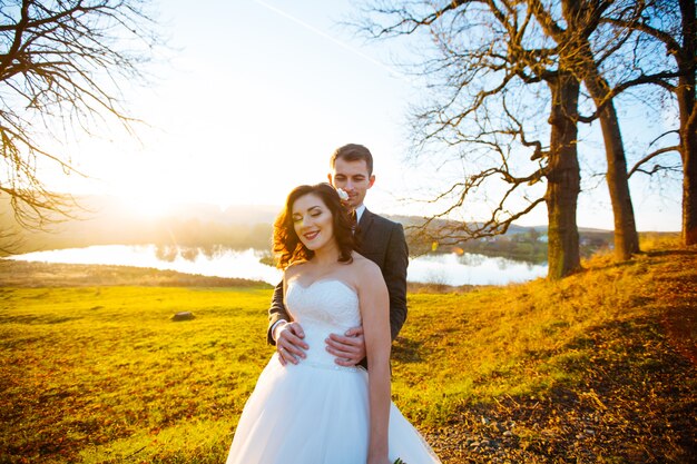 Beautiful happy stylish bride with elegant groom on the space of beautiful trees in the autumn park