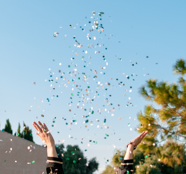 Beautiful happy woman at celebration party with confetti falling everywhere on her