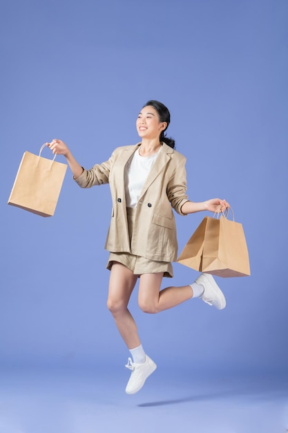 Beautiful happy woman holding shopping bags isolated on purple