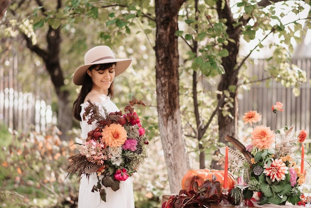 美しい幸せな女性は彼女の手に花とハーブの花束を持っています