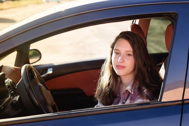 A beautiful happy woman is sitting in the car car dealership
car rental and sale