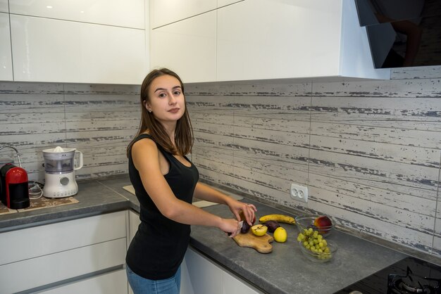 Beautiful happy woman on kitchen making fruits salad. concept of healthy food