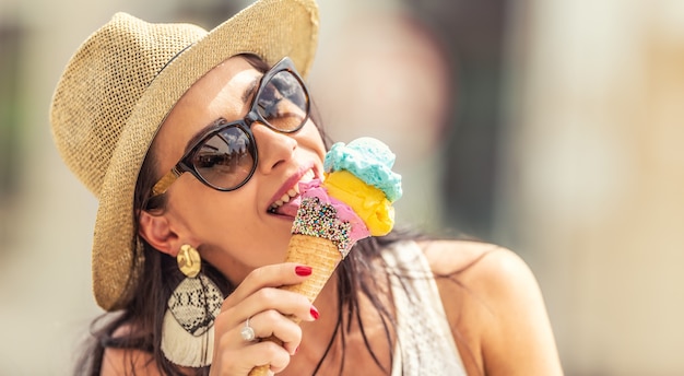 美しい幸せな女性は、暑い夏の日にアイスクリームをなめます。