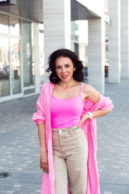 beautiful happy woman in pink fashion shirt walking at city street