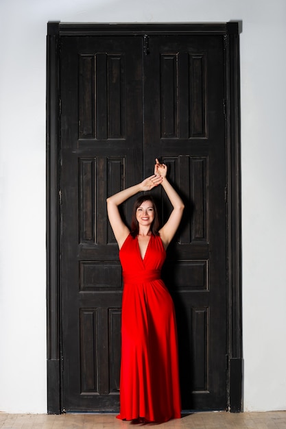 Beautiful happy woman in red dress in interior, sensual portrait