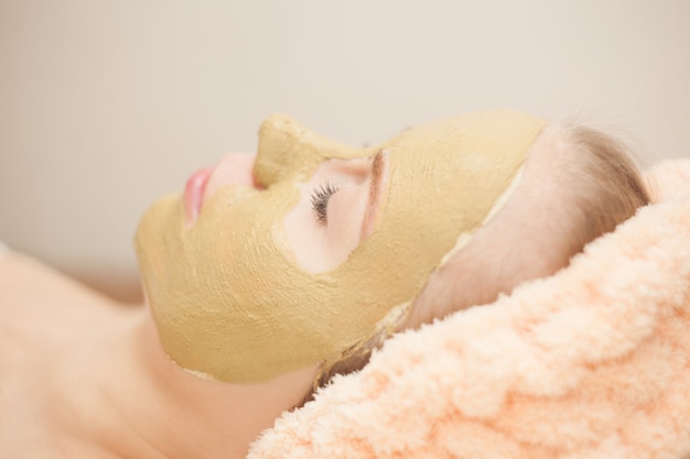 Beautiful happy woman in the spa making face mask treatment.selective focus