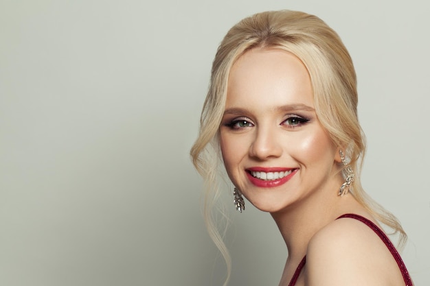 Beautiful happy woman with blonde hair and makeup om white background