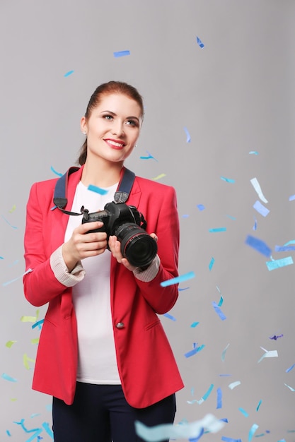 Beautiful happy woman with camera at celebration party with confetti Birthday or New Year eve celebrating concept