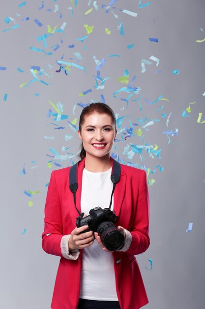 Beautiful happy woman with camera at celebration party with confetti Birthday or New Year eve celebrating concept