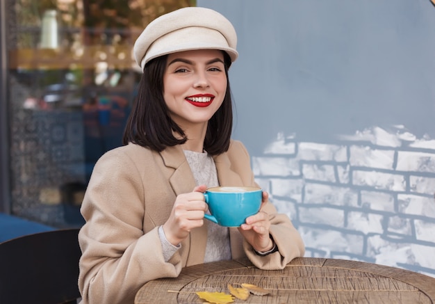 Beautiful happy woman with a cup of coffee in a cafe