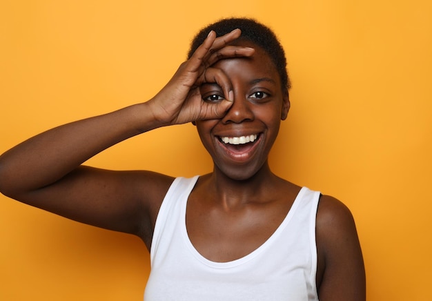 Beautiful happy young african woman isolated over yellow background