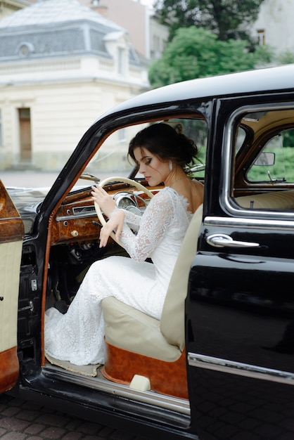 Красивые счастливые молодые жених и невеста, глядя из ретро авто