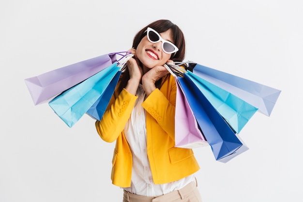 beautiful happy young business woman posing isolated over white wall holding shopping bags.