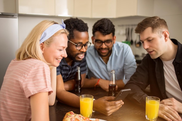 Photo beautiful happy young caucasian blonde woman sitting at table with her friends, laughing looking at smartphone. multi ethnic students testing new gadget. technology, friendship, leisure concept.