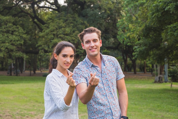 Beautiful happy young couple making heart shape with hand outdoor