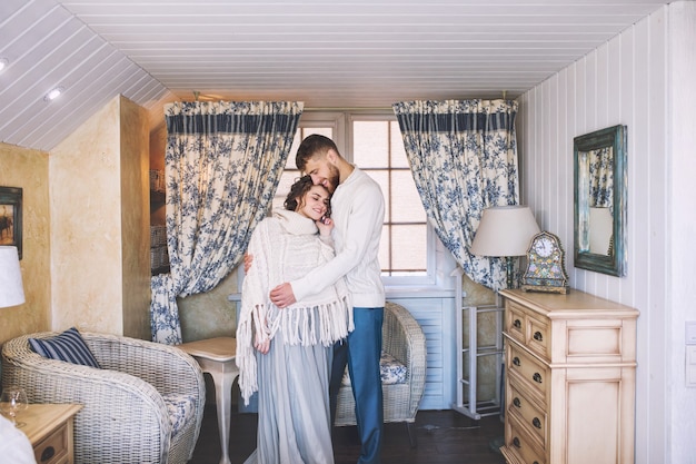 Beautiful and happy young couple man and woman at home in a cozy white interior