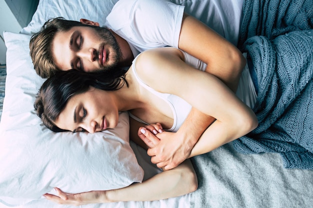 Красивая счастливая молодая пара спит в постели по утрам и обнимается. Концепция любви и отношений