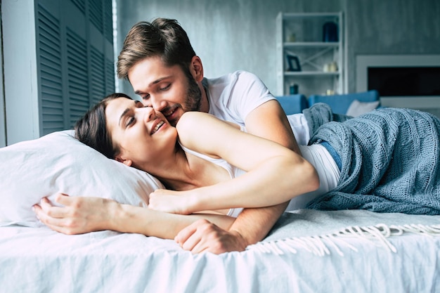 Beautiful happy young couple sleeping in bed in the morning and hugging. Love and relationships concept