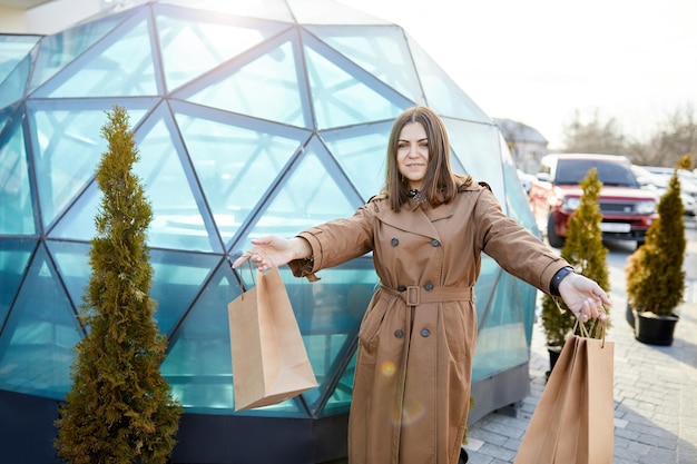 Beautiful happy young girl walking with shopping bag on city streets while doing shopping Stylish girl smiling walking along the street