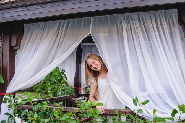 Beautiful happy young slender long-haired blonde girl in gazebo.