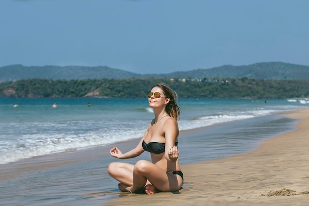 Beautiful happy young woman in bikini on sandy ocean beach