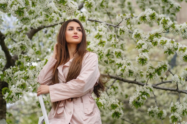 Beautiful happy young woman enjoying smell in a flowering spring garden