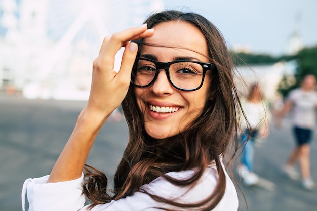 屋外を歩きながら街の広場で楽しい時間を過ごしている眼鏡の美しい幸せな若い女性