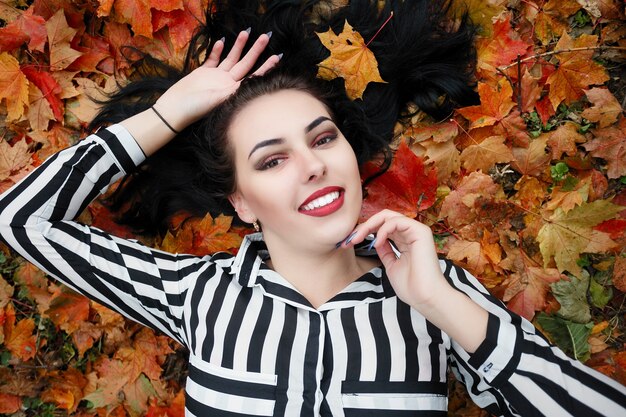 Beautiful happy young woman having fun with leaves in park