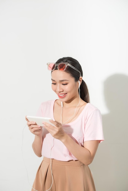 아름 다운 행복 한 젊은 여자는 음악을 듣고 흰색에 고립 된 모바일 응용 프로그램을 사용