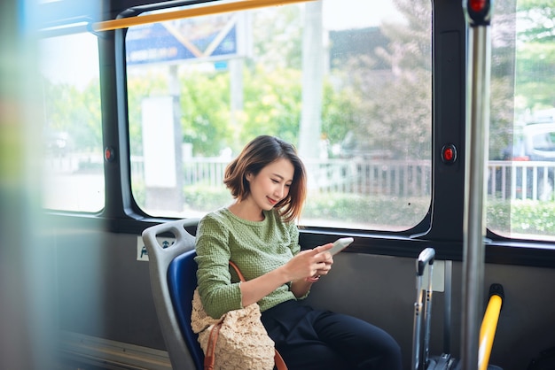 아름 다운 행복 한 젊은 여자 시내 버스에 앉아 휴대 전화를 보고