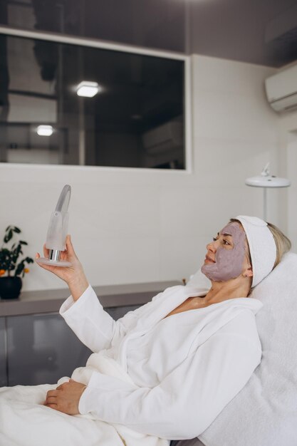 Beautiful and happy young woman sitting in medical chair and looking in the mirror She