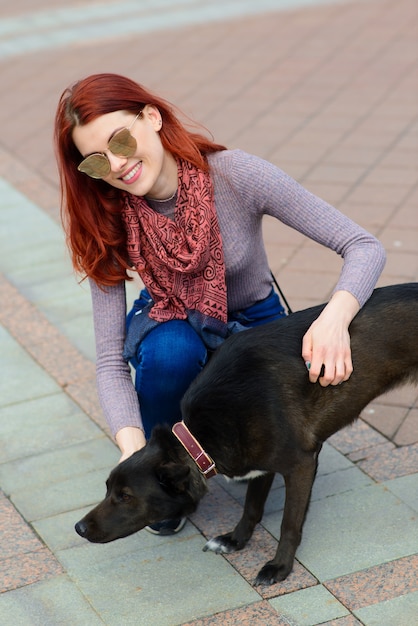 かわいい黒犬と美しい幸せな若い女性は、通りで楽しい時を過します。動物と人との友情の概念。