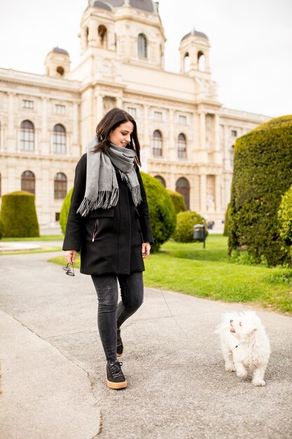 Beautiful happy young woman with cute small dog puppy have fun on street