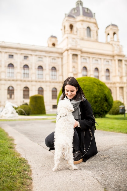 Beautiful happy young woman with cute small dog puppy have fun on street