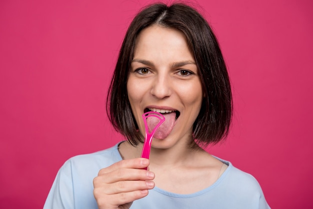 Beautiful happy young woman with tongue scraper