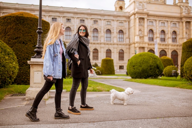 Beautiful happy young women with cute small dog puppy have fun on street of Vienna, austria