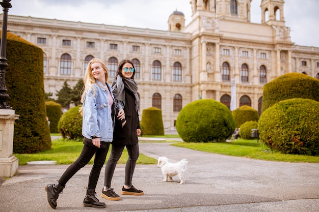 かわいい小型犬の子犬と美しい幸せな若い女性は、オーストリアのウィーンの通りで楽しんでいます