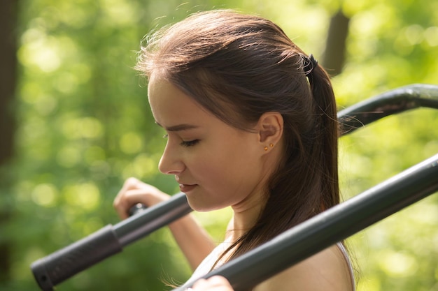 美しく健康な体若い女の子が公園でシミュレーターに従事しています