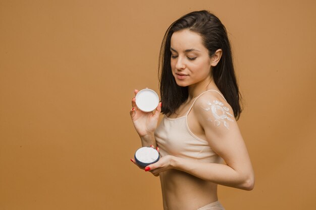 Foto ragazza bella e sana con crema per il corpo, corpo giovane e in forma che posa in biancheria intima. sport, fitness, dieta, nutrizione e concetto di assistenza sanitaria.