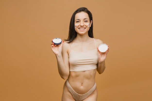 Beautiful and healthy girl with body cream, young and fit body posing in underwear