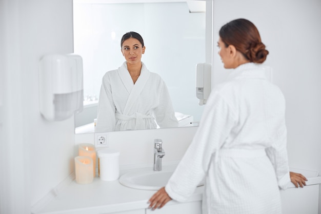 Beautiful healthy smiling caucasian woman taking care of her skin in the bathroom