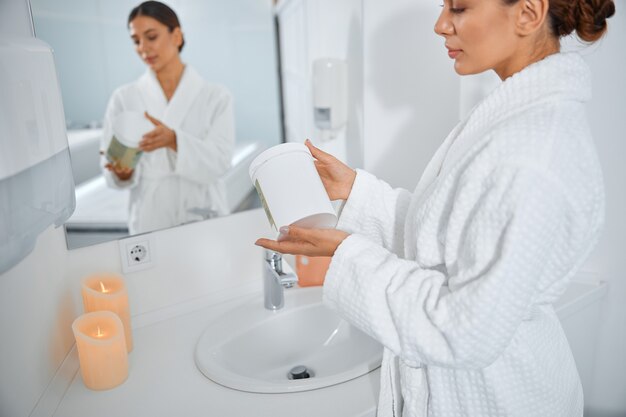 Bella donna caucasica sorridente in buona salute che si prende cura della sua pelle in bagno