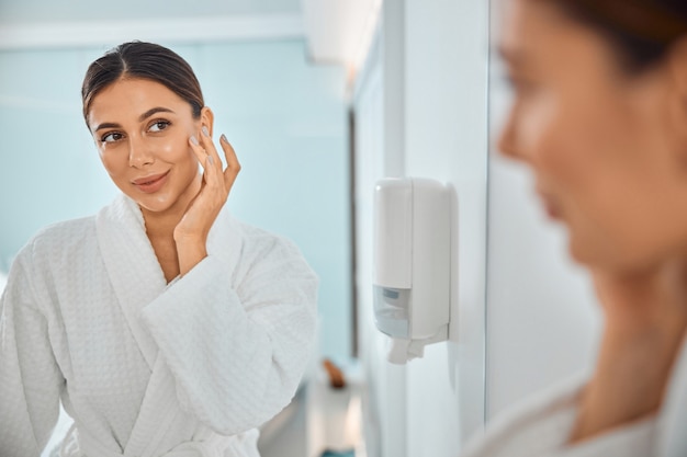 Beautiful healthy smiling caucasian woman taking care of her skin in the bathroom