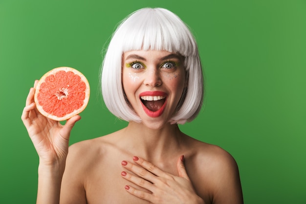 Beautiful healthy young topless woman wearing short white hair standing isolated, showing sliced grapefruit