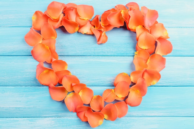 Photo beautiful heart of rose petals on wooden background