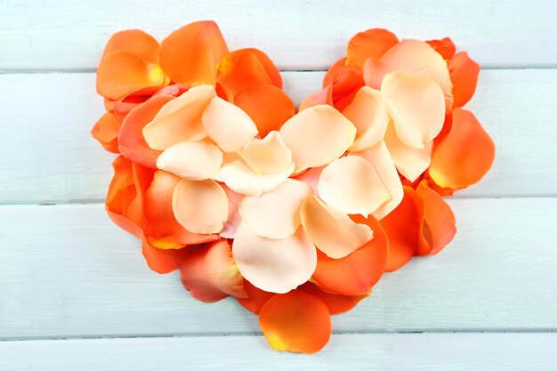 Beautiful heart of rose petals on wooden background